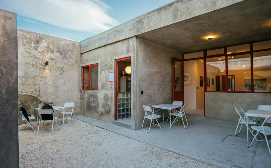 Patio de hormigón con mesas y sillas junto a una casa