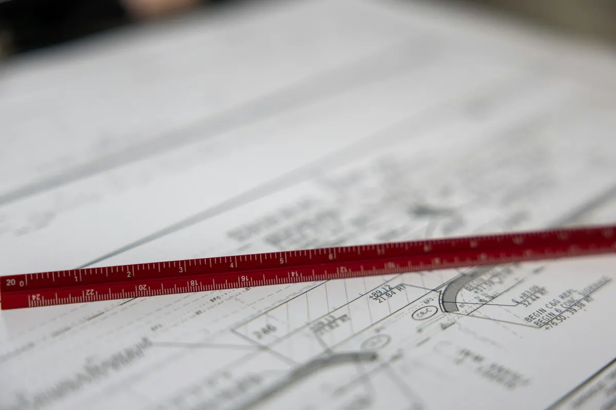 Regla metálica roja sobre planos de construcción